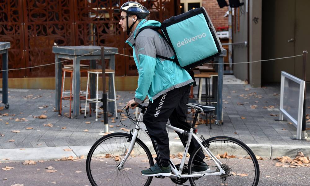 A Deliveroo rider cycles on a city centre street.jpg