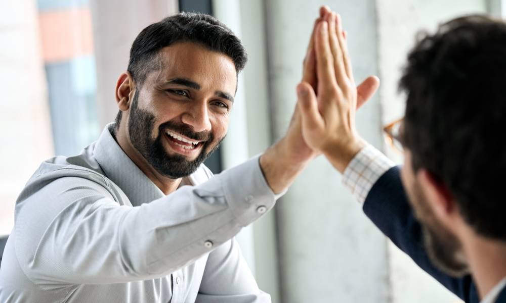 Two men high five how tech can help promote workplace mental health.jpeg