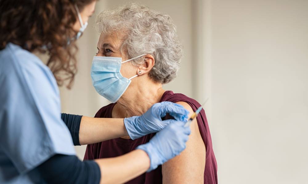 Nurse holding syringe vaccinating senior woman (1).jpg