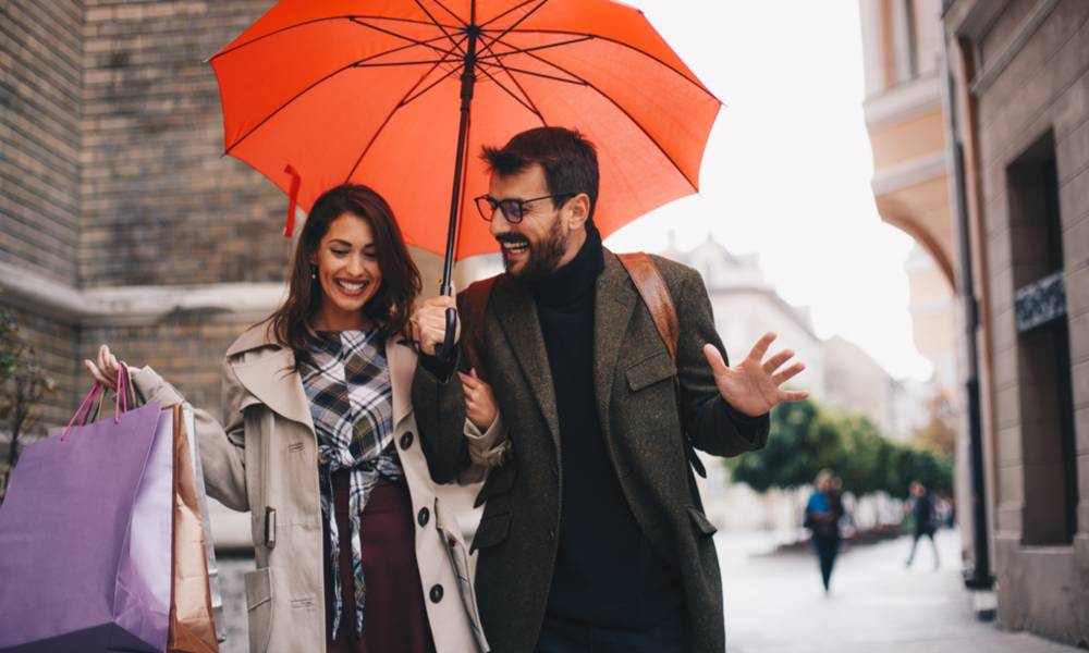 Woman carrying shopping bags links arms with man under an umbrella (1).jpg