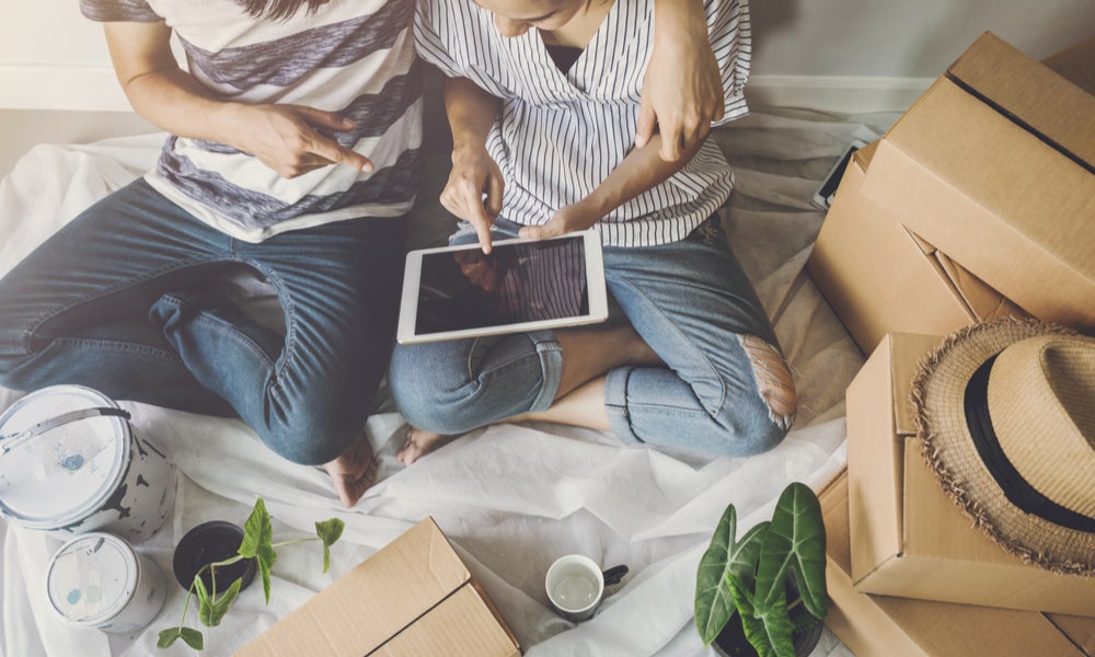 Couple in new home online shopping surrounded by plants, paint and cardboard boxes-min.jpg