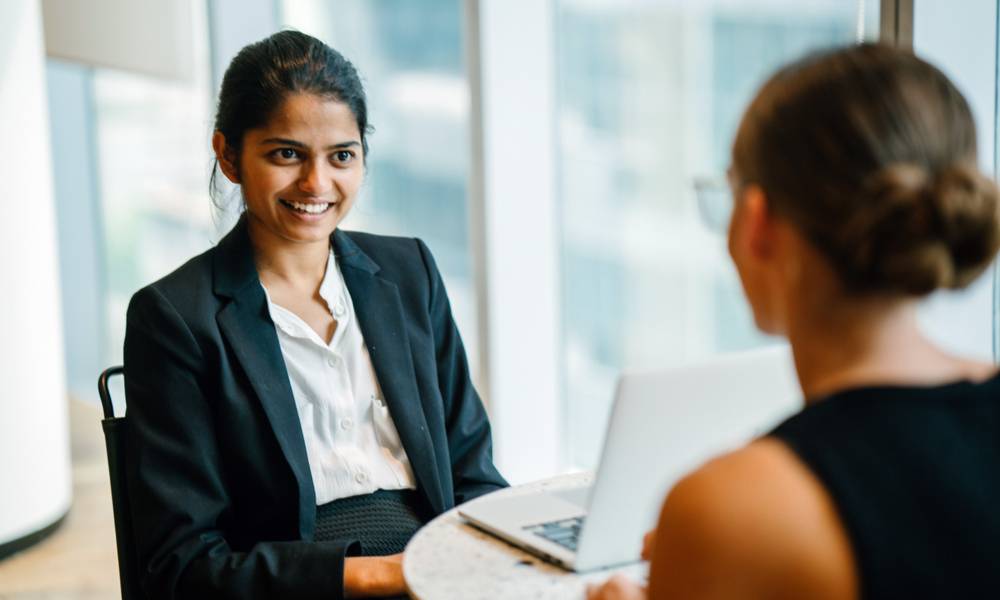 A young Indian Asian woman has a business meeting (interview) with a Caucasian white woman in an office during the day..jpg