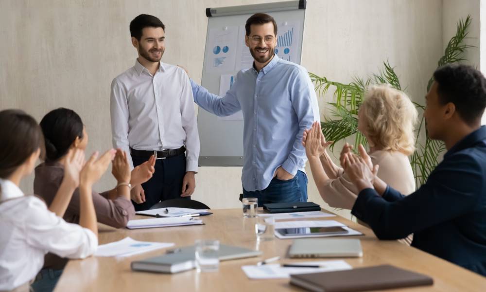 Happy young businessman introduces new male employee newcomer at office meeting, man boss congratulate worker with promotion or achievement, colleagues applaud (1).jpg