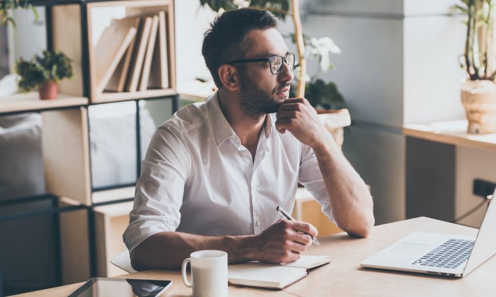 Thoughtful mature leader holding pen and looking away while sitting at his working place in office.jpg