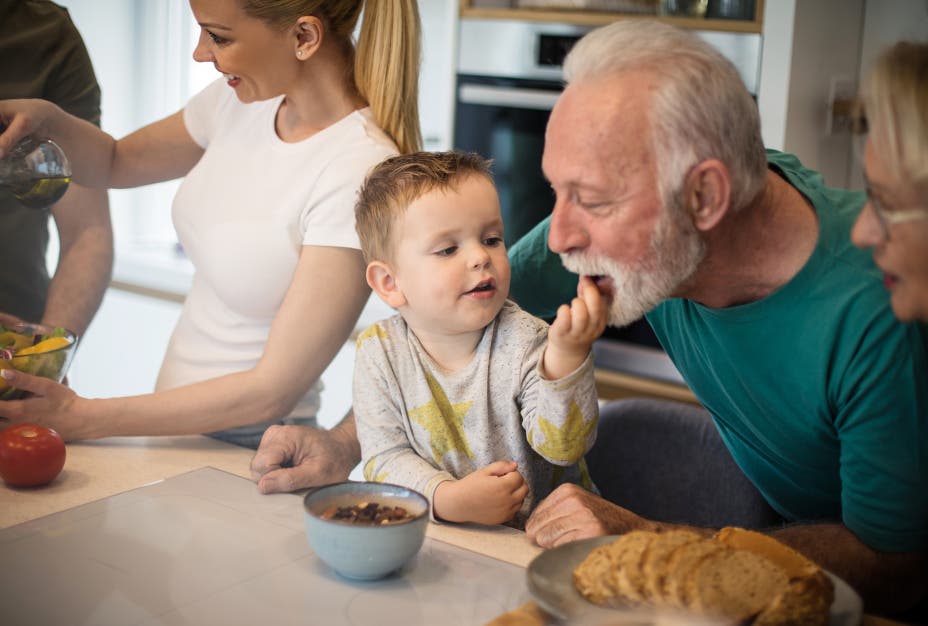 Grandson feeds grandpa snacks from a bowl