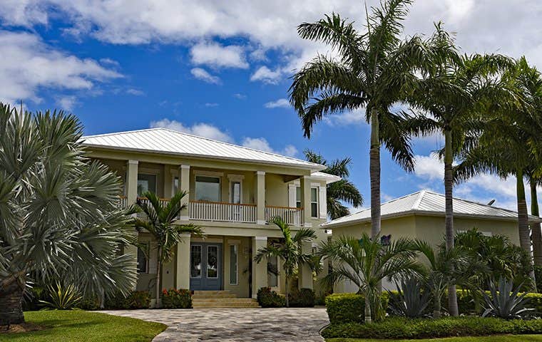 a beige two story house with palm trees in front