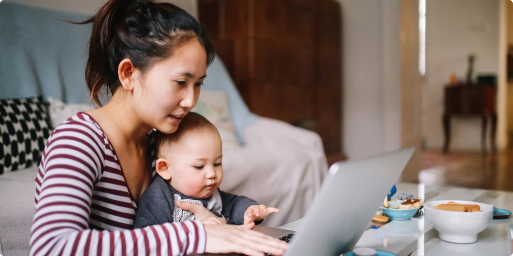 Mother working on a laptop while minding her child.