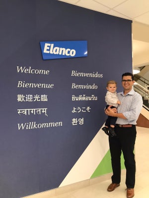 un empleado sostiene a su hijo frente al letrero de bienvenida a Elanco
