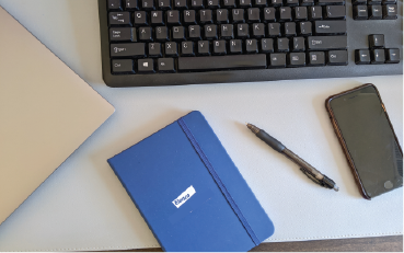 a picture of a keyboard, notebook, pen and phone