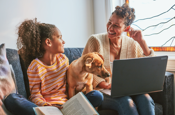 a mom and a daughter hold a dog and looking at a computer