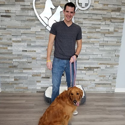 a man smiling at the camera holding his dog on a lead