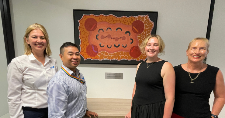 Team standing with 'Harmony' image by Annie Roberts (Waralungku Arts, Borroloola)