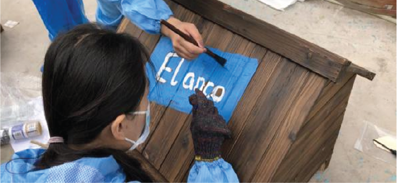 Elanco employees painting the Elanco logo on a box