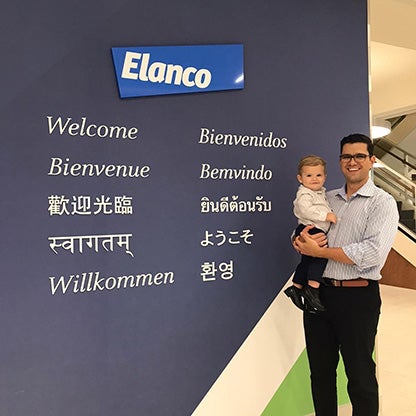 a male holding a baby smiling next to an Elanco welcome sign