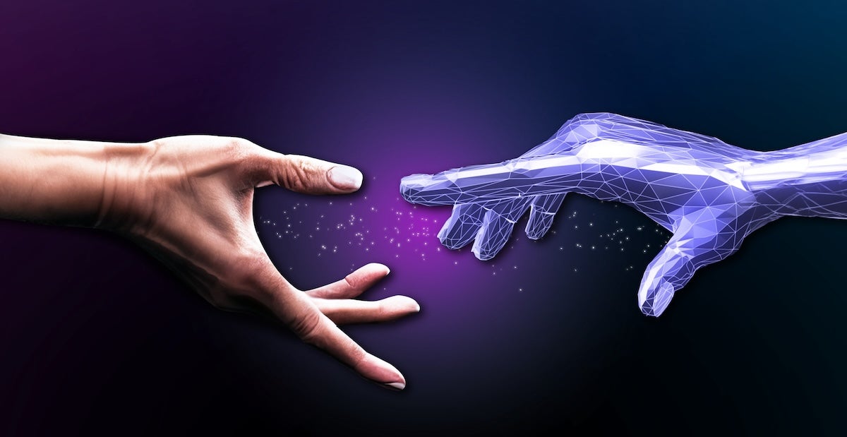 A human hand reaches out towards a blue, digital-looking hand