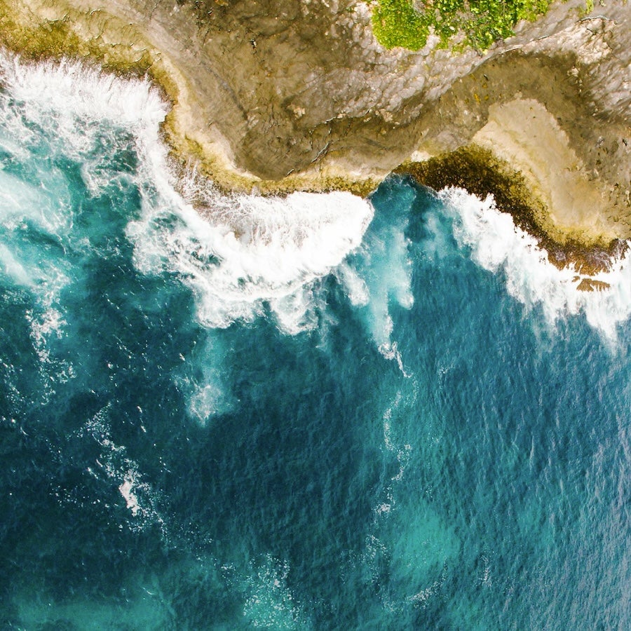 An aerial view of waves crashing against a cliff