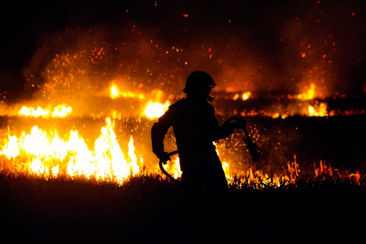 A firefighter silhouetted against a wildfire