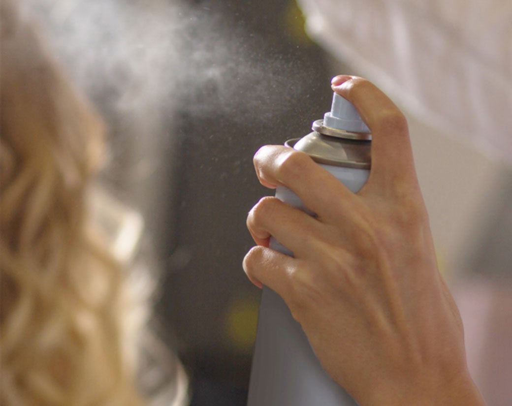 hand spraying an aerosol can of hairspray