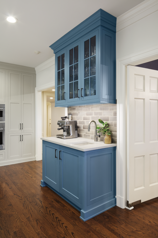 A blue coffee bar in a white kitchen adds a touch of uniqueness to the space.