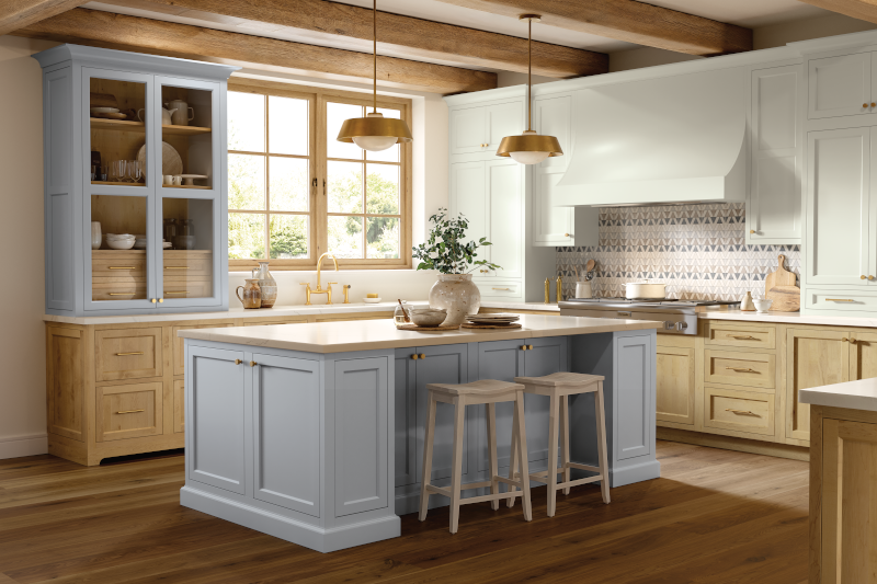 A kitchen with a mix of stained wood cabinets and painted light blue cabinets.