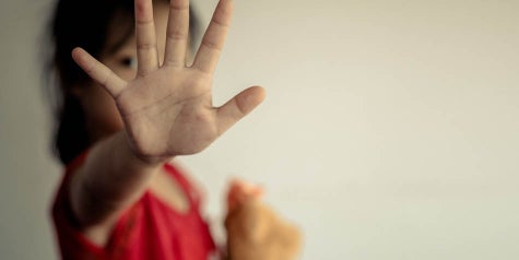 Small child, a girl, hiding her face putting her hand out to say stop