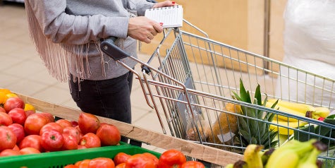 Walking around grocery store with a cart and list, next to produce section