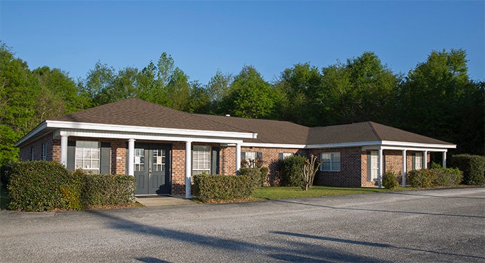 Century Medical Center Front entrance. Red Brick building brown roof there are shrubs and gray shutters.