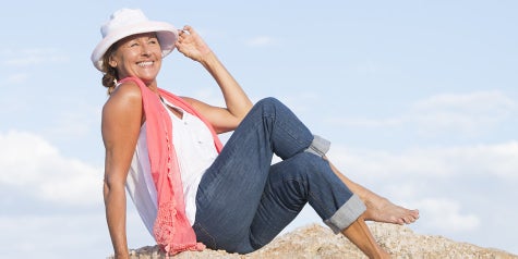 Women on beach with sitting on sand smiling.