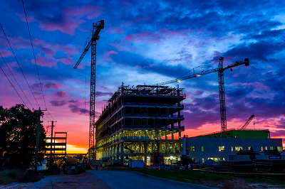 Building under construction at sunset under a colorful sky of clouds that appear blue, purple, orange and various other colors