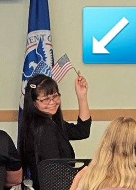 Cathy proudly waves American flag after taking oath to be a U.S. citizen.