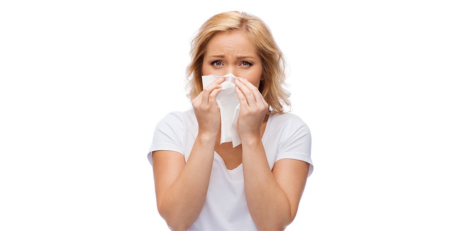 Woman sneezing into tissue