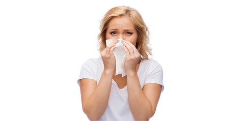 Woman sneezing into tissue