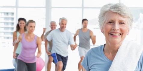 Fitness group class with elderly lady in front smiling.