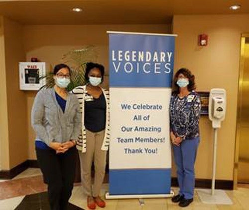 Three members of the outpatient registration pose next to a sign. 