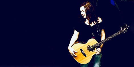 Stephanie Hill, first patient, holds her guitar