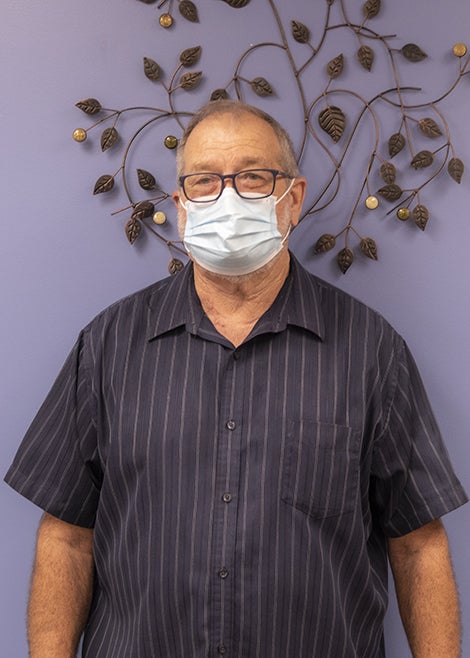 Head and shoulders photo of Harvey Radcliff wearing a mask and a gray striped button up shirt.