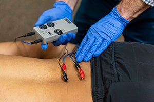Therapist using electric stimulation on a functional dry needling patient.