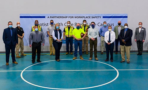 A group of leaders from Brasfield & Gorrie and Baptist Health Care in masks at OSHA signing