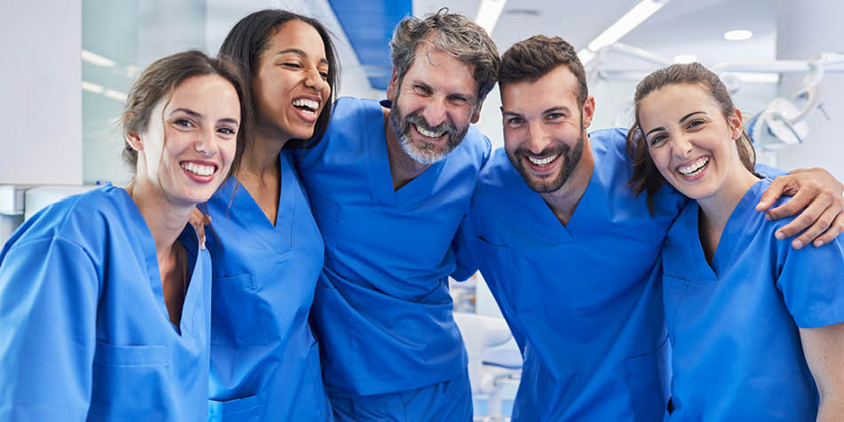 Five people working in the medical professional world gathering and smiling