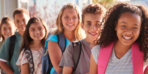 Kids at school standing in a line with backpacks on