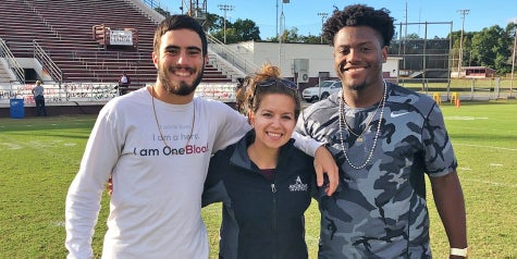 Athletic Trainer poses with student athletes at local high school.