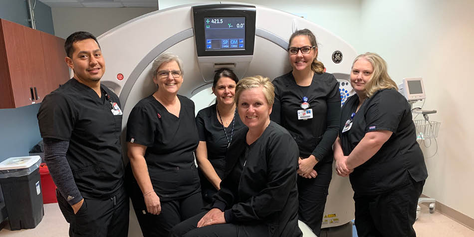 Cancer screening team is pictured in front of their CT equipment