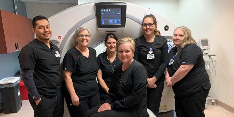 Cancer screening team is pictured in front of their CT equipment