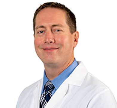 General surgeon Dr. Seth Vernon in a white coat with blue shirt and tie.