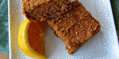Pumpkin oat bar with slick of lemon on plate.