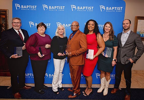 Seven people standing side by side holding awards