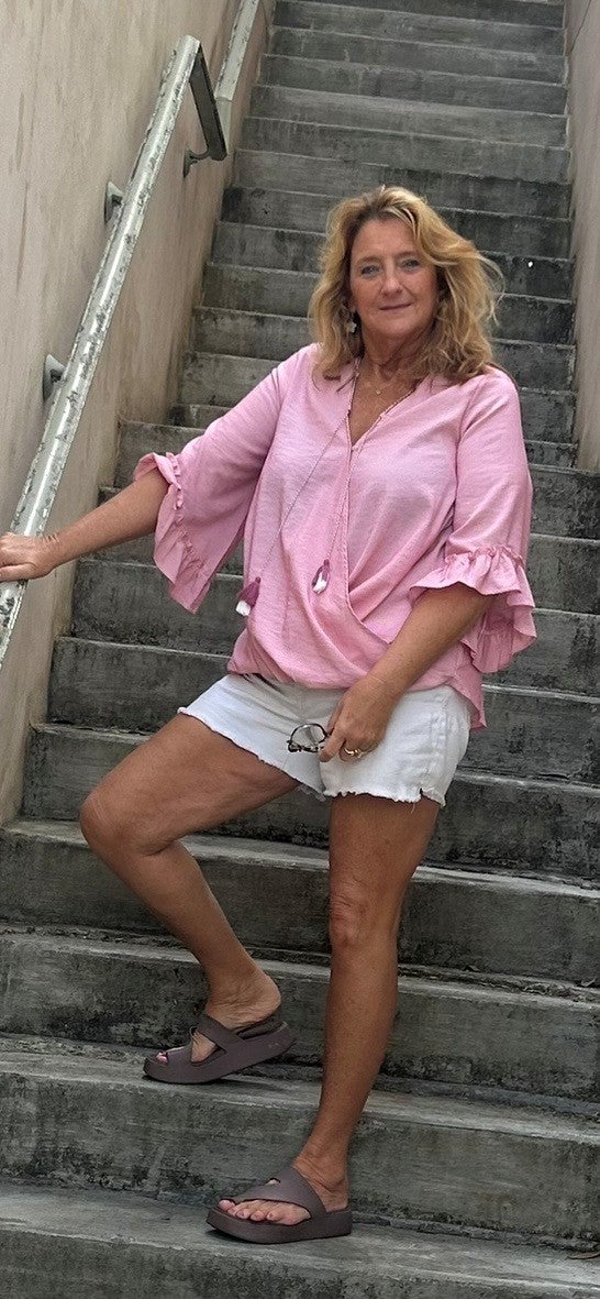 ECMO patient Marianne smiling standing on staircase in pink blouse.