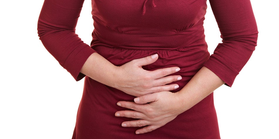 Woman in red dress holding her stomach in discomfort.