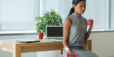 Female using and lifting weights at her work near the desk