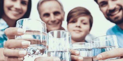 Family holding up glasses of water ready to drink
